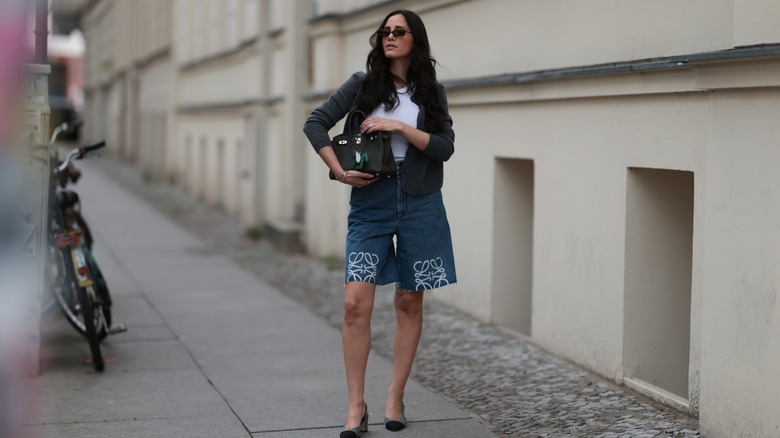 Une femme portant un long short en jean avec un haut et une veste blancs
