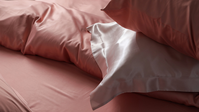 Taies d'oreiller en soie empilées sur des draps en soie