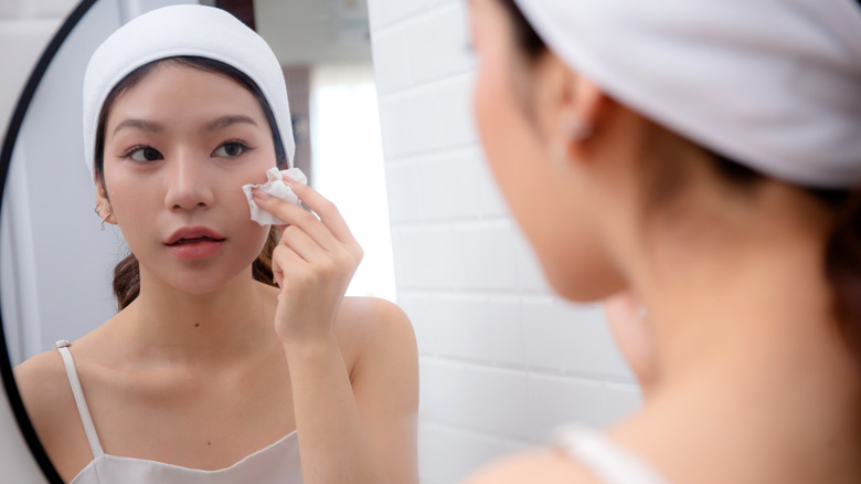 Une femme se démaquille devant le miroir