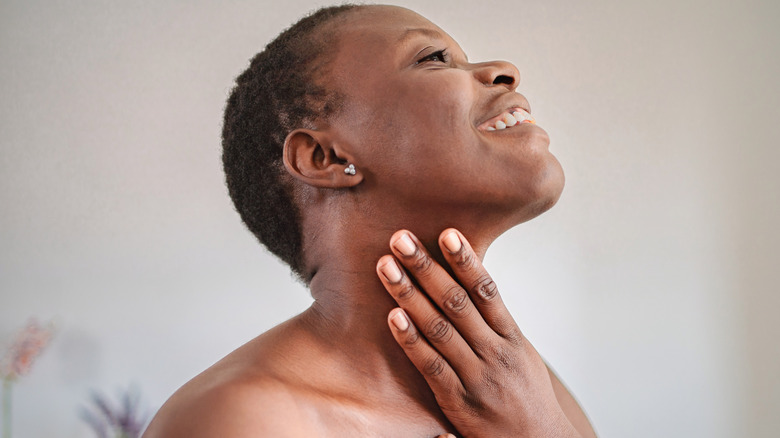 Une femme noire appliquant une crème hydratante sur son cou