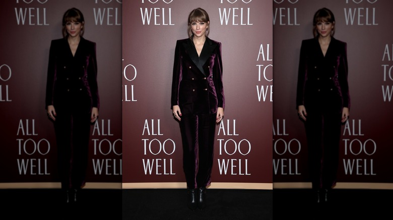 Taylor Swift pose vêtue d'un costume en velours bordeaux