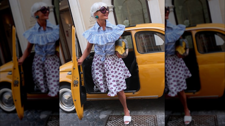 Grece Ghanem dans une chemise bleue et une jupe à motifs sortant d'un taxi
