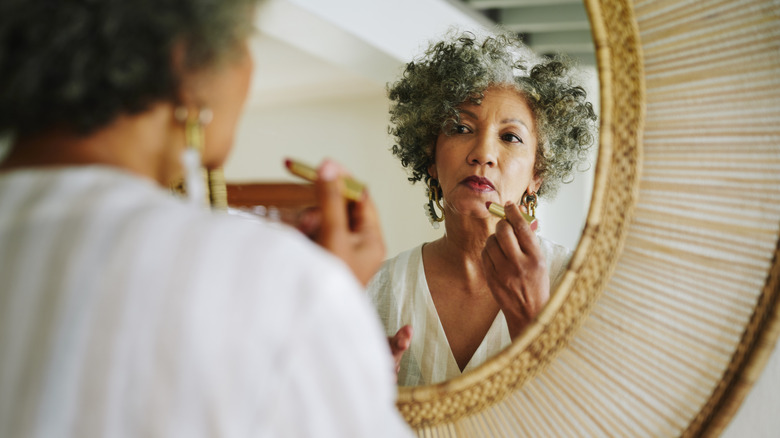 Femmes aux cheveux gris bouclés se maquillant dans un miroir en bambou