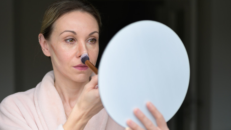 Femmes appliquant le contour et rougissant sur son visage