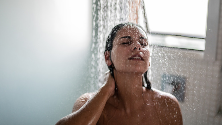 Une femme dans un soutien-gorge noir se brossant les cheveux mouillés après une douche