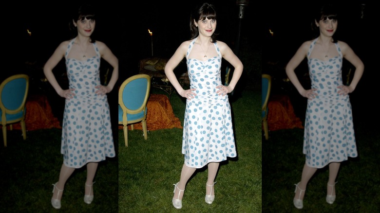 Zooey Deschanel posant avec sa main sur ses hanches tout en portant une robe bleue et blanche lors d'un événement en 2003