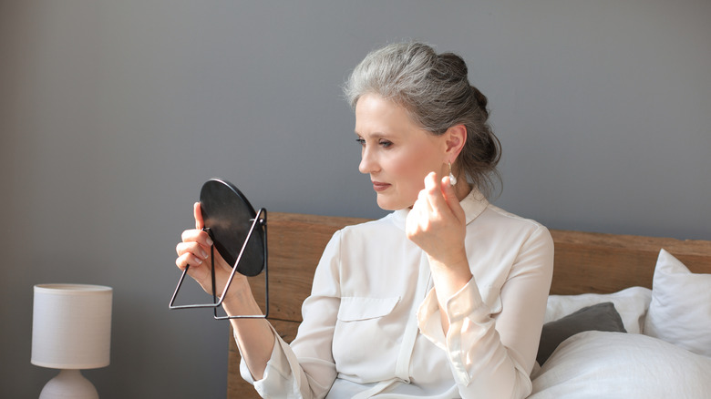 Femmes plus âgées admirant son maquillage dans un petit miroir