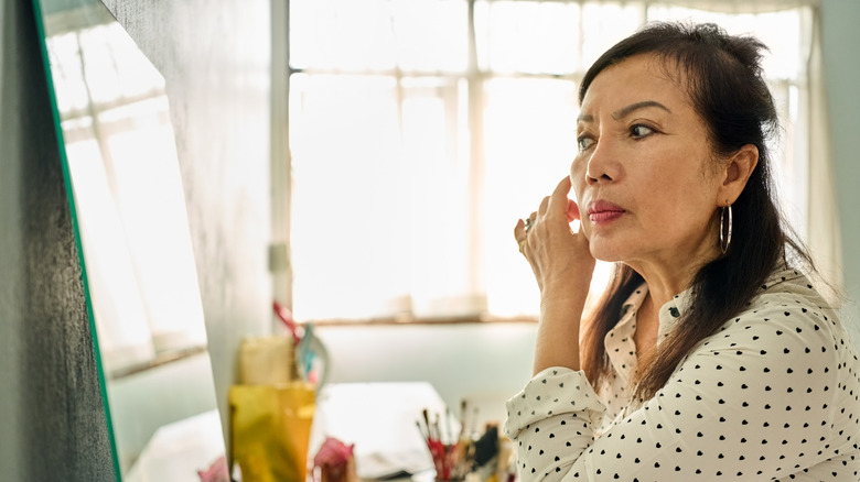 Les femmes plus âgées à la recherche dans le miroir portant un chemisier à pois coeur