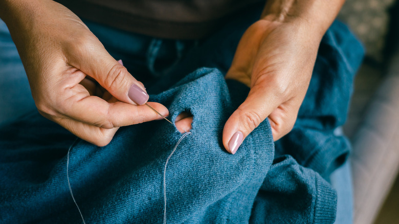 Mains réparant un trou dans un pull