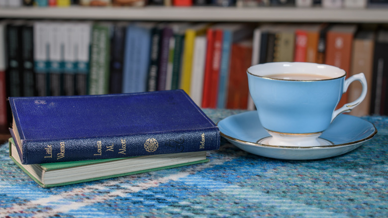 Pile de livres de Louisa May Alcott avec une tasse de thé