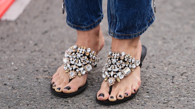 Une femme portant un jean cloisonné avec des tongs ornées