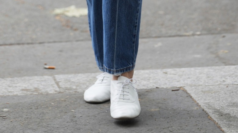 Une femme portant un jean cloisonné avec des baskets blanches sobres