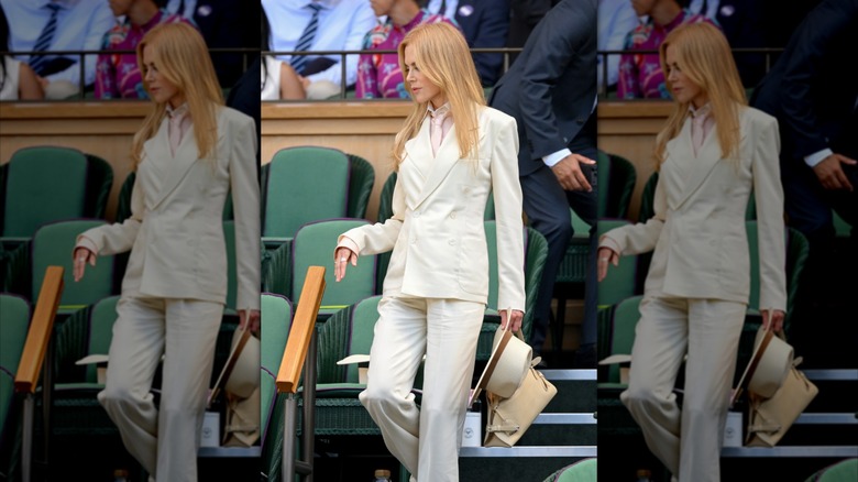 Nicole Kidman descendant les marches des tribunes de Wimbledon et vêtue d'un costume blanc slim