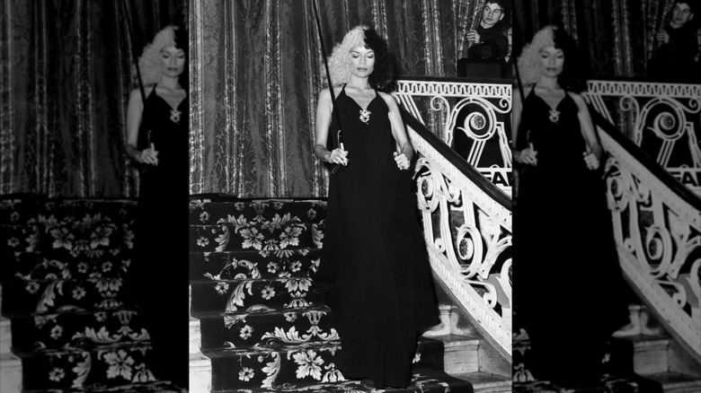 Bianca Jagger dans une perruque noire et blanche avec une canne et une robe noire lors d'un bal