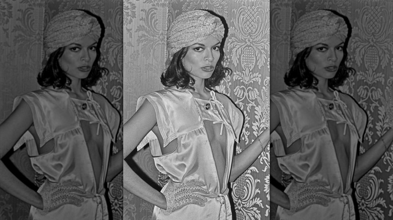 Bianca Jagger portant un turban et une robe blanche avec des découpes lors d'un événement
