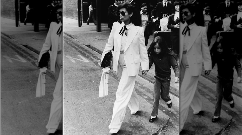 Bianca Jagger traversant la route dans un costume blanc avec un nœud papillon noir