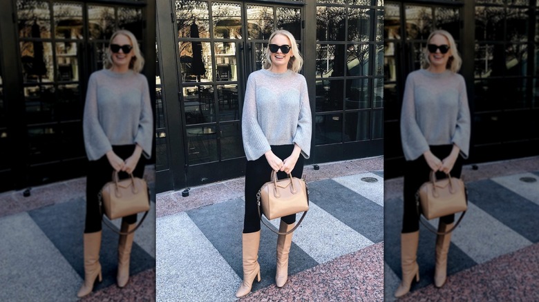 Une femme debout dans la rue vêtue d'un pull gris transparent et portant des bottes hauteur genou