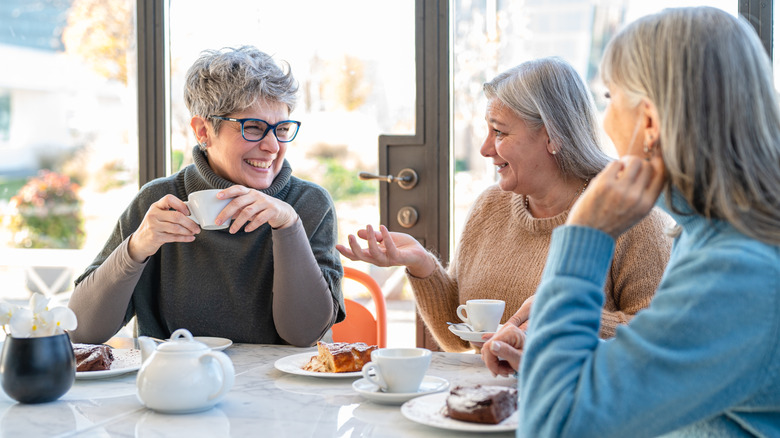 Trois femmes âgées discutant autour de la table en buvant du café