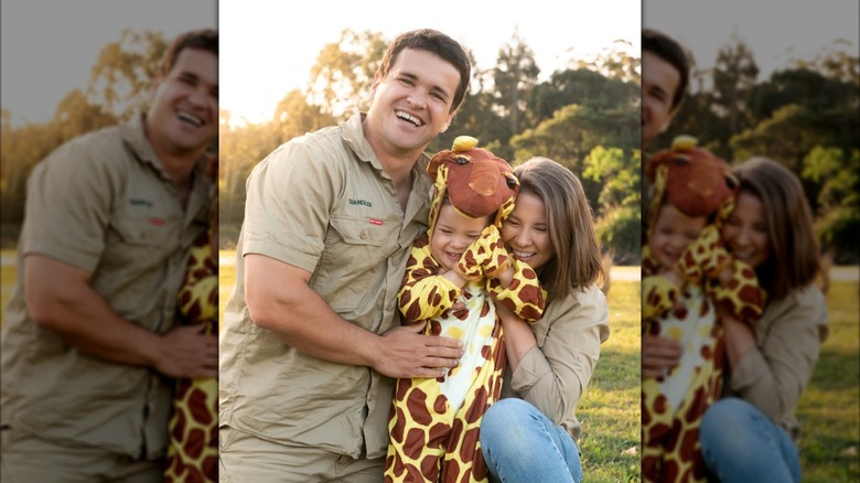 Bindi Irwin et Chandler Powell serrent dans leurs bras leur fille Grace, une petite fille vêtue d'un costume de girafe