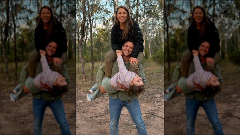 Bindi Irwin assise sur les épaules de Chandler Powell alors qu'il tient leur fille Grace dans ses bras