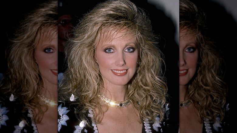 Morgan Fairchild avec des cheveux blonds et un collier ras du cou doré