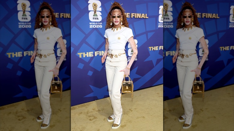 Winnie Harlow portant une ceinture dorée avec une tenue blanche sur le tapis rouge de la Coupe du monde