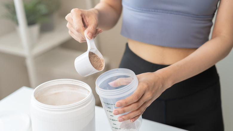 Une femme met une cuillerée de poudre dans un shaker