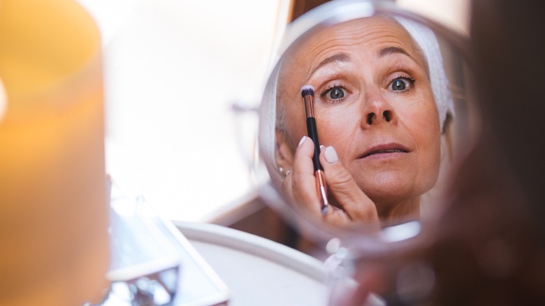 Femme appliquant du fard à paupières sur la paupière supérieure avec un pinceau à fard à paupières double face