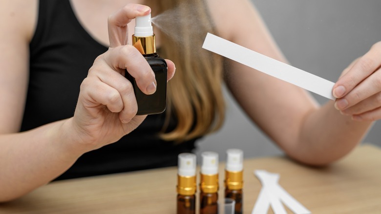 Une femme vaporisant du parfum sur des cartes d'échantillons de parfum