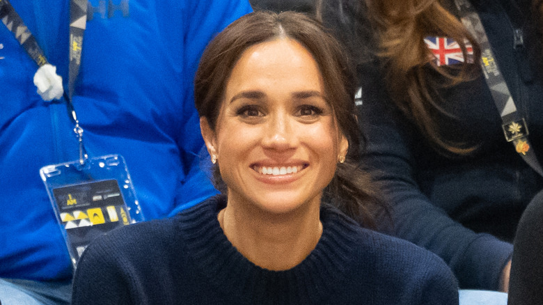 Meghan Markle souriante aux Jeux Invictus vêtue d'un pull bleu