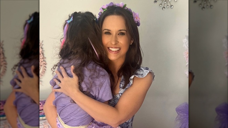 Lacey Chabert souriante en tenant sa fille dans ses bras