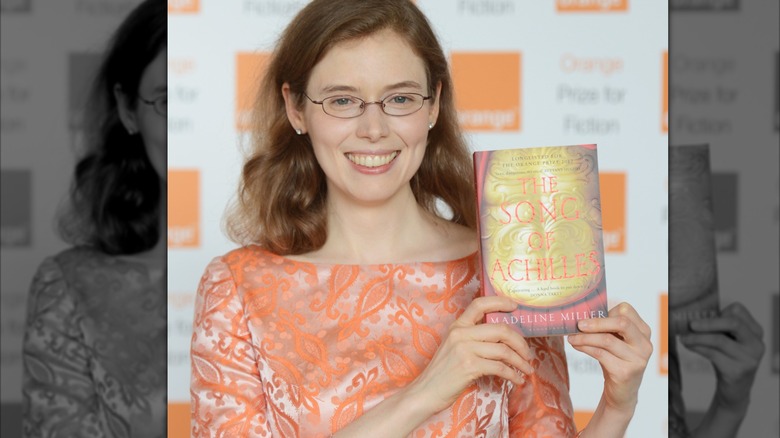 Madeline Miller lève son livre en souriant