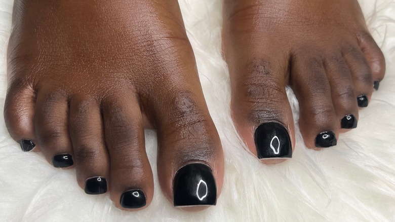 Les pieds d'une femme avec une longue pédicure noire