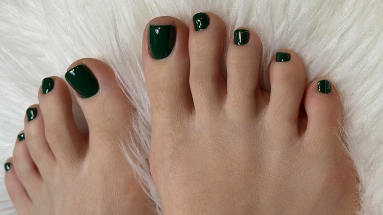 Deux pieds sur une couverture moelleuse avec une pédicure vert foncé
