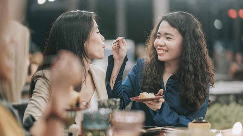 Une fille donne à une autre fille une assiette de nourriture