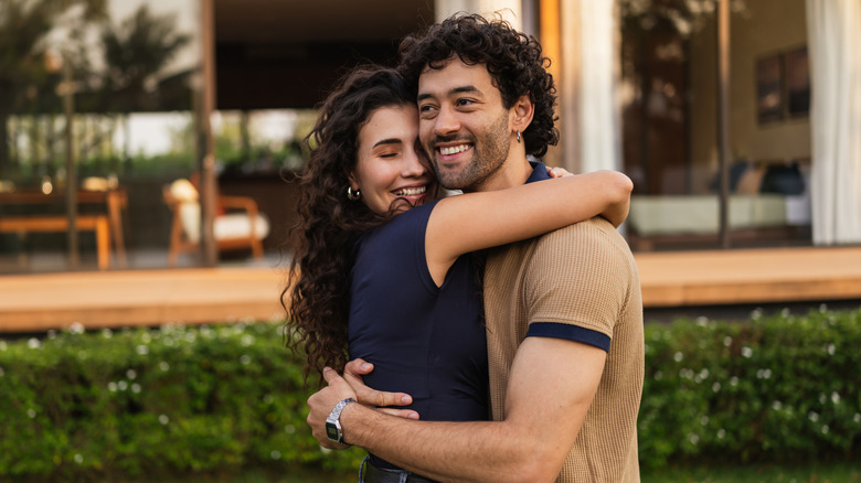 Un couple s'embrasse devant une maison