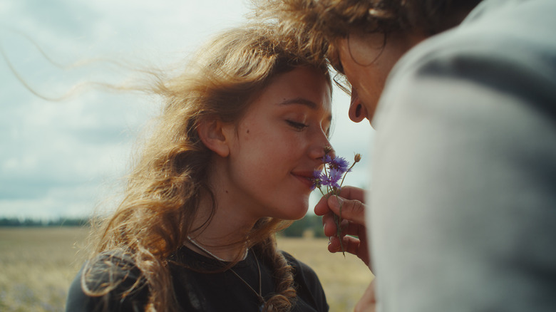 Une fille aux cheveux bouclés sent les fleurs violettes