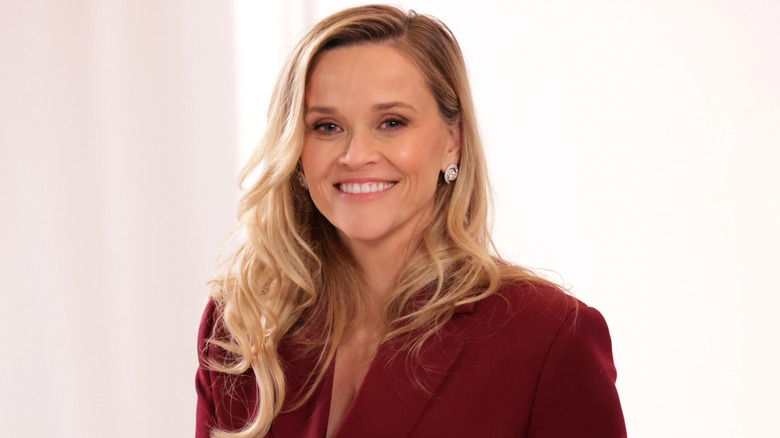 Reese Witherspoon souriante dans un blazer rouge