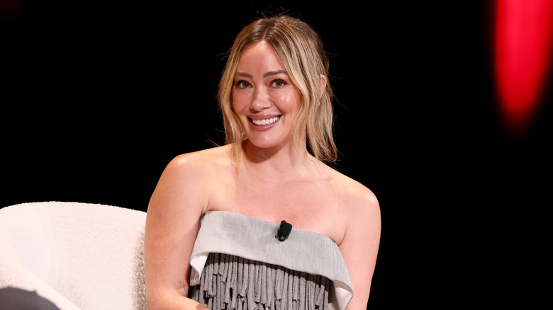 Hilary Duff assise sur une scène