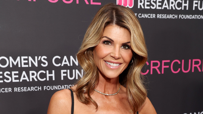 Lori Loughlin portant un tour de cou et une robe noire à bretelles