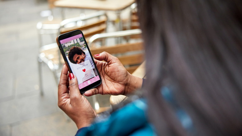 Femme invisible tenant un téléphone avec une application de rencontres ouverte et un prétendant potentiel à l'écran