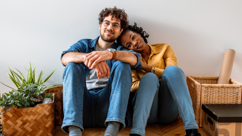 Couple heureux assis contre un mur uni, entouré d'objets en mouvement