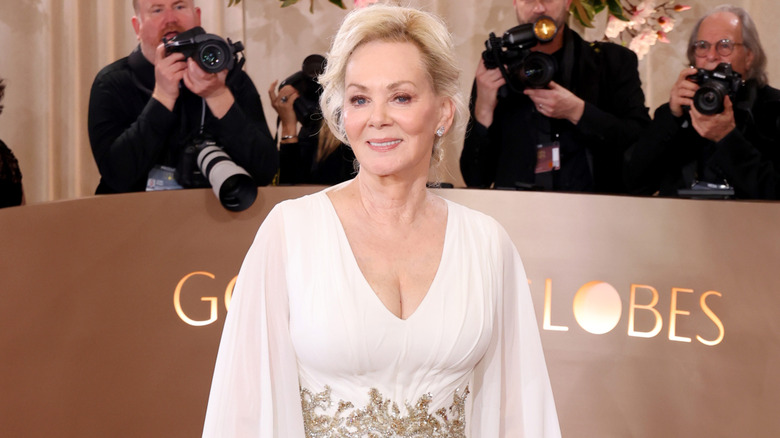 Jean Smart dans une robe blanche avec une ceinture dorée autour de la taille et les cheveux relevés