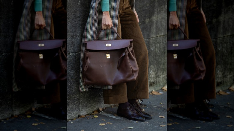 Une femme tenant un sac à main marron et portant des chaussures derby marron