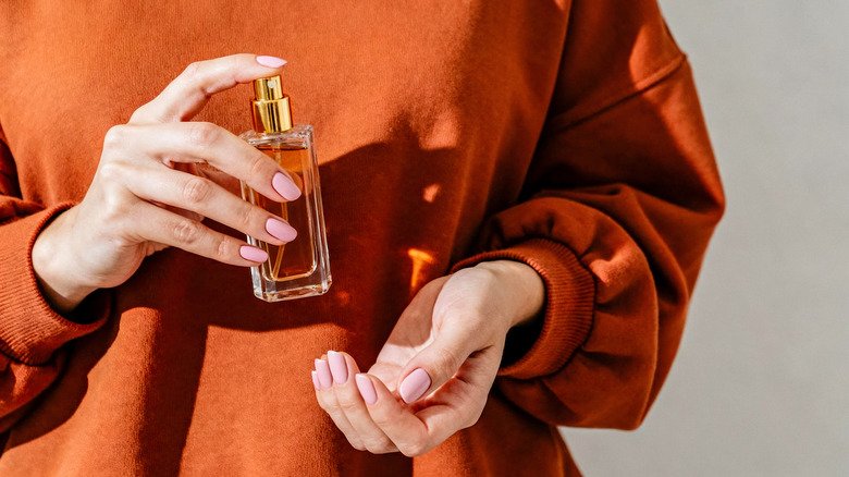 Une femme vaporisant du parfum sur son poignet