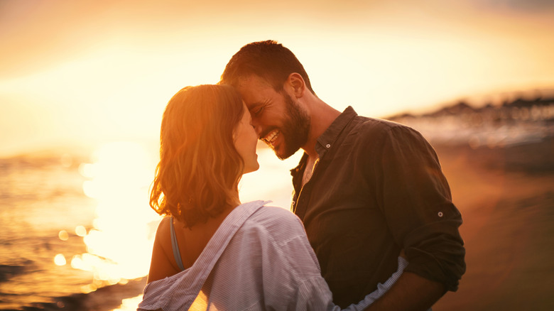 Jeune couple se regardant sur la plage au coucher du soleil tardif.