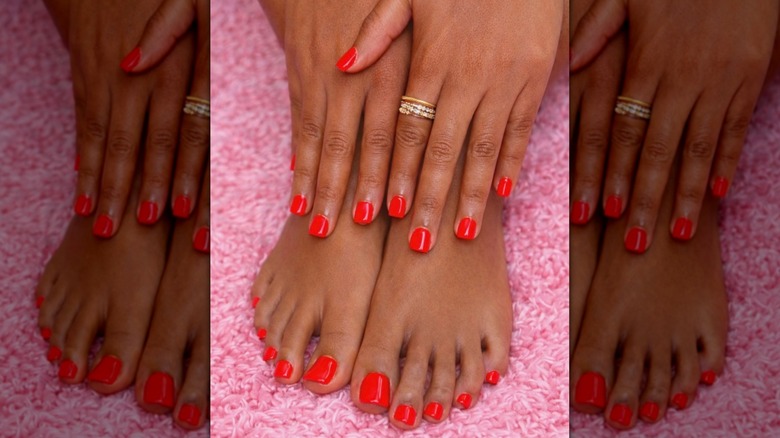 Mains et pieds contre un jeté rose montrant une manucure-pédicure rouge vif