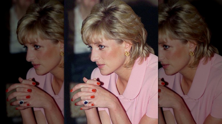 Gros plan de la princesse Diana laçant ses doigts devant elle tout en portant une manucure rouge sur ses ongles