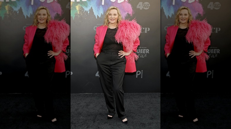 Kim Cattrall sur le tapis rouge vêtue de noir avec une veste rose vif