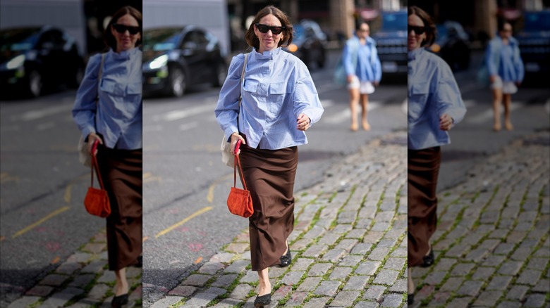 Une femme marchant dans les rues dans une chemise bleue avec une jupe marron